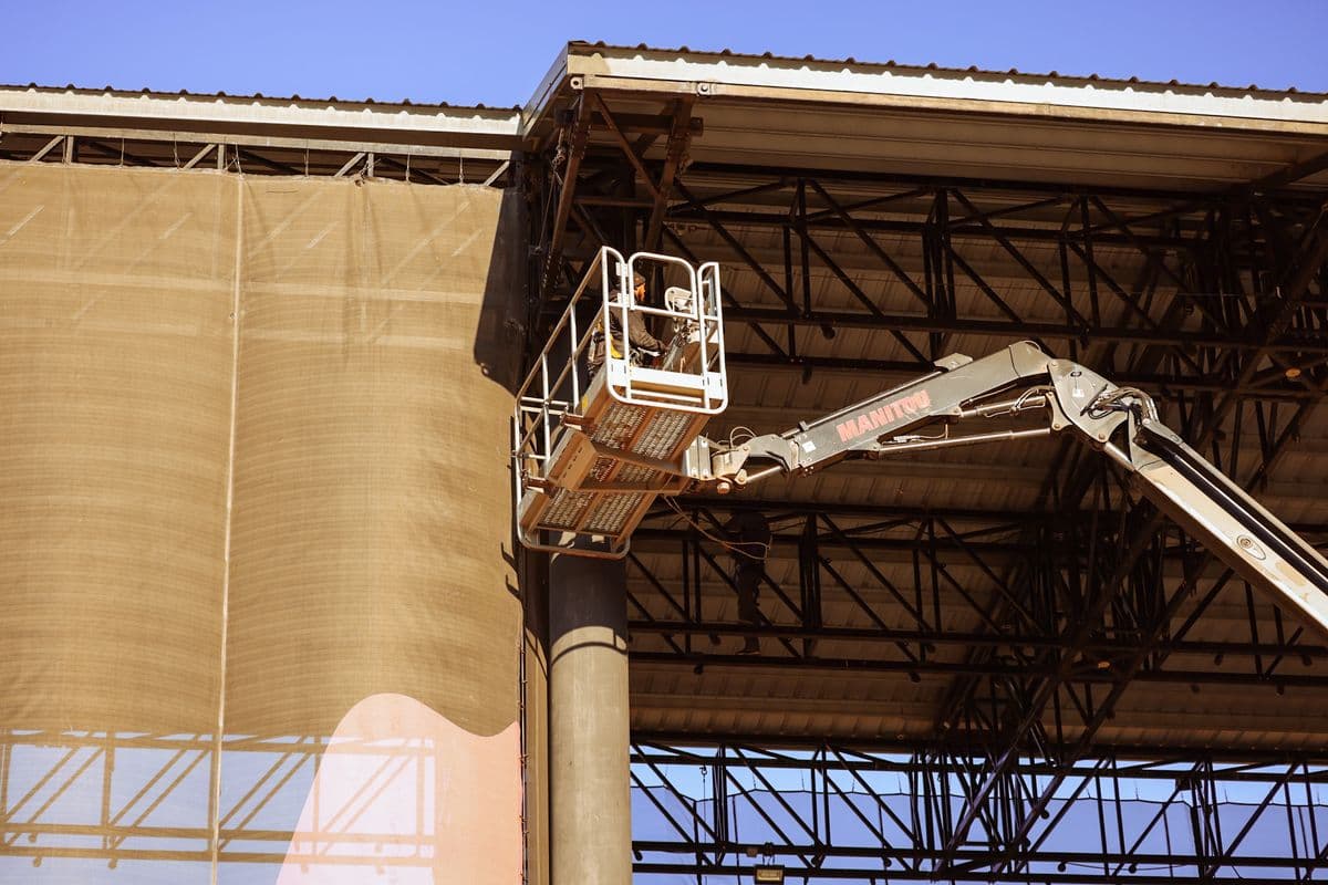 Boom lift reaching the overhead steel of an amphitheater roof structure