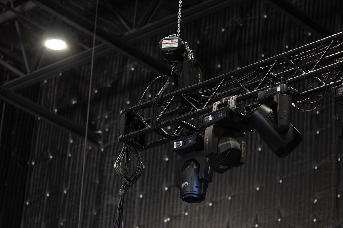 Truss fitted with moving lights flown above a venue floor